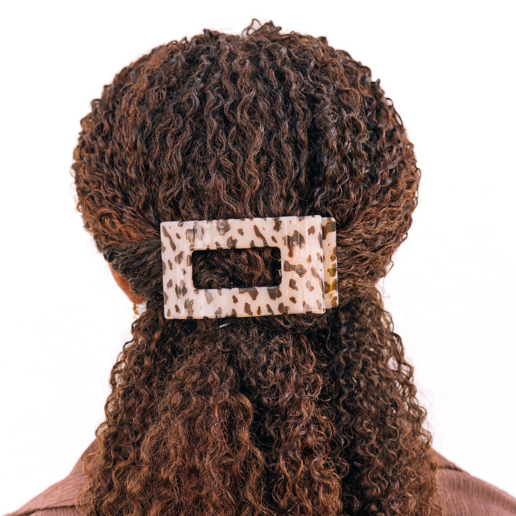 Blonde tortoise rectangular hair clip holding curly brown hair in a half-up style