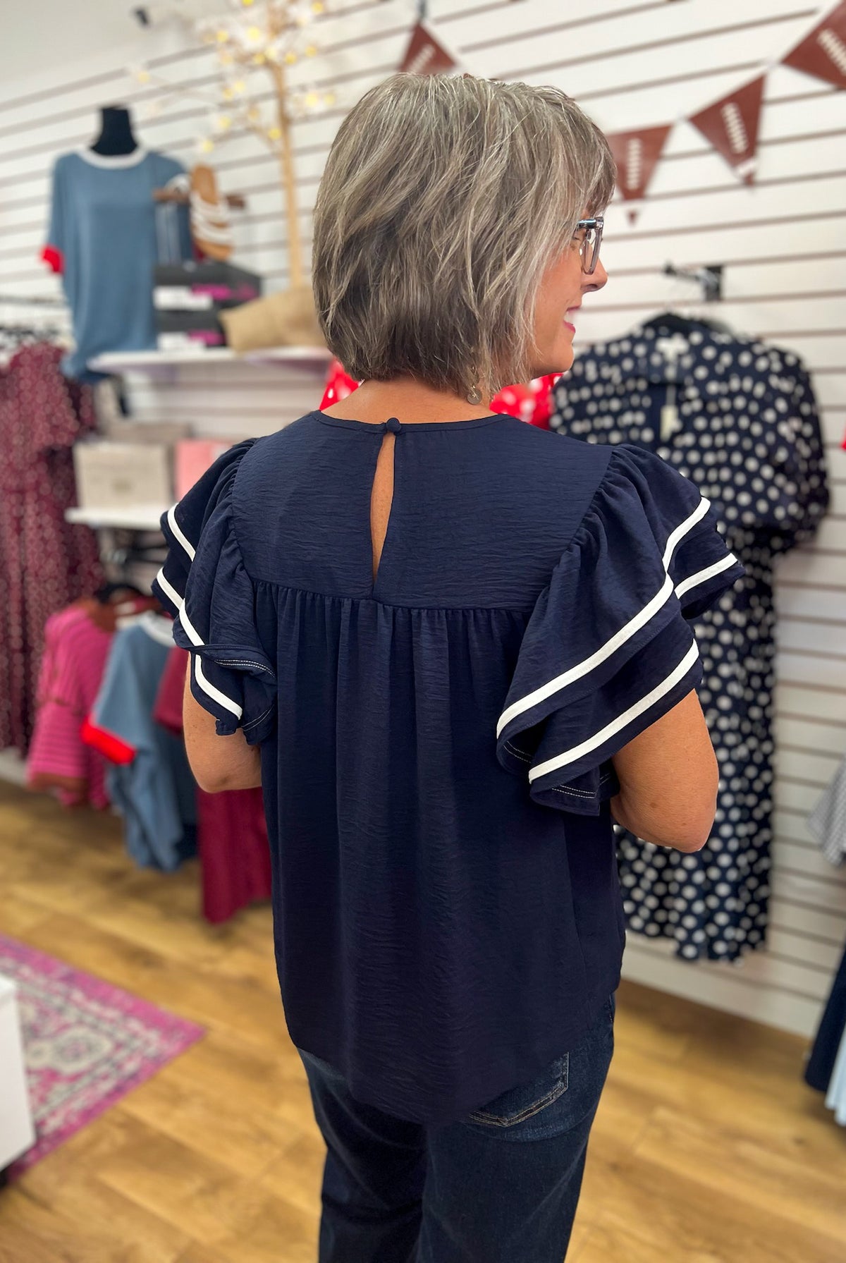 Navy blue ruffle sleeve top with white contrast piping, back view