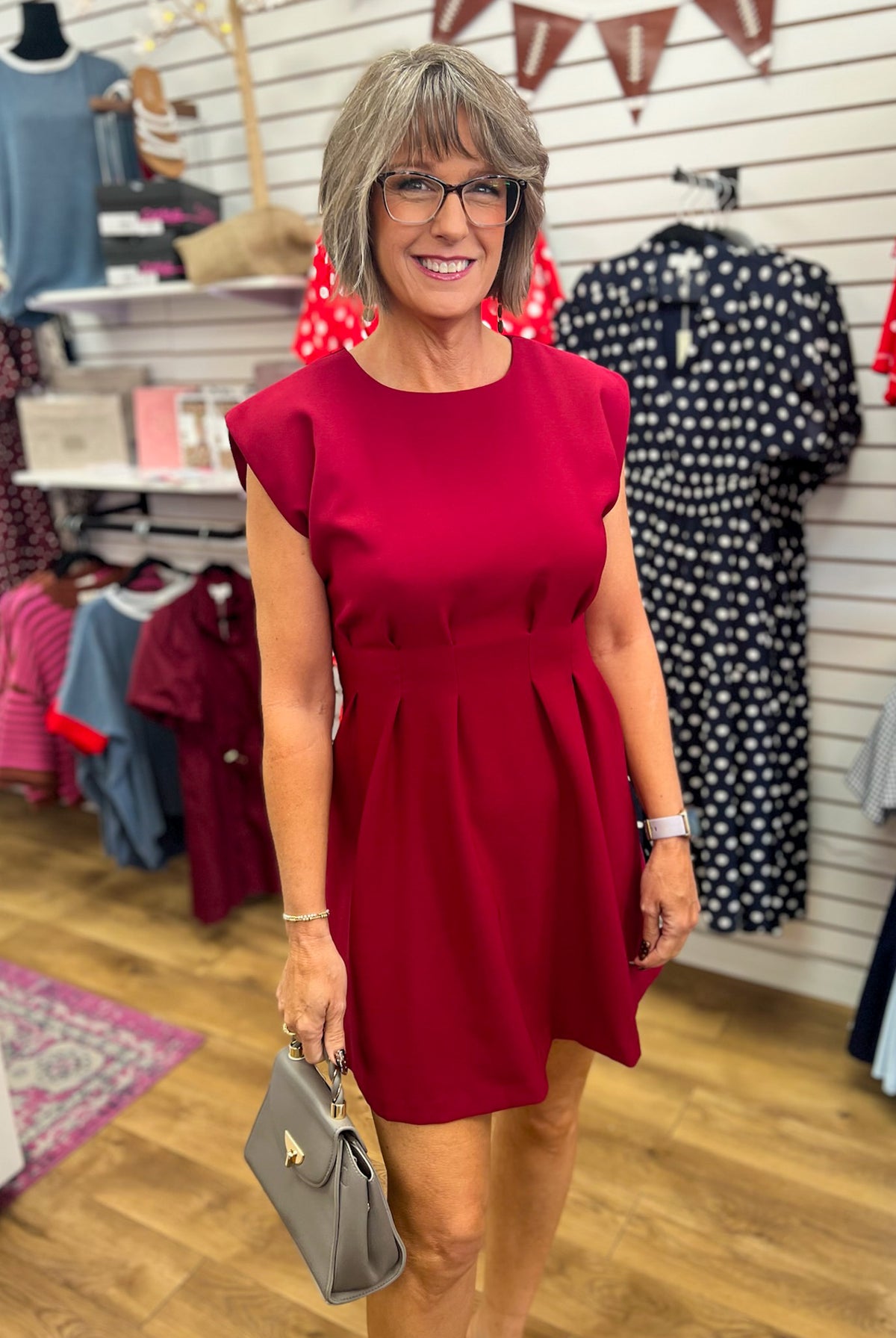 Burgundy sleeveless A-line dress with pleated waist and structured shoulders