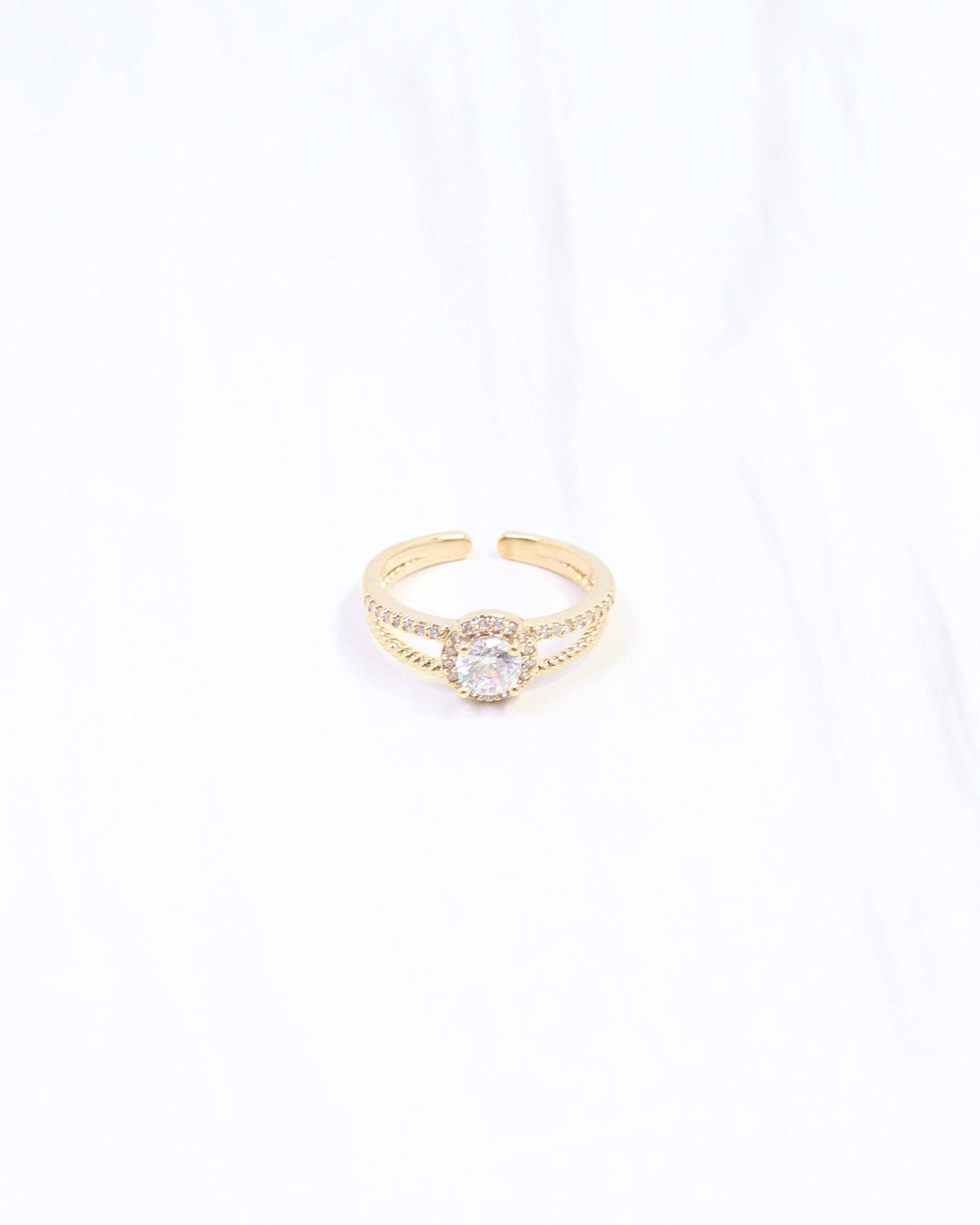 Gold adjustable ring with round CZ center stone and halo setting on white background