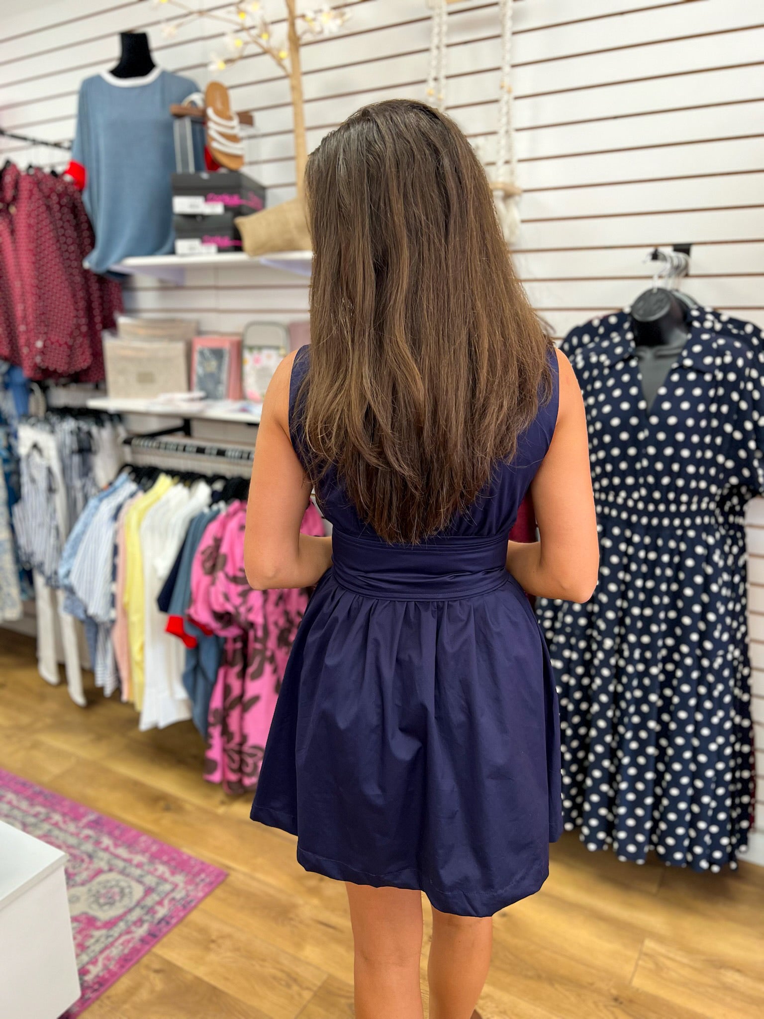 Navy blue sleeveless fit-and-flare dress with ruched waist belt, back view