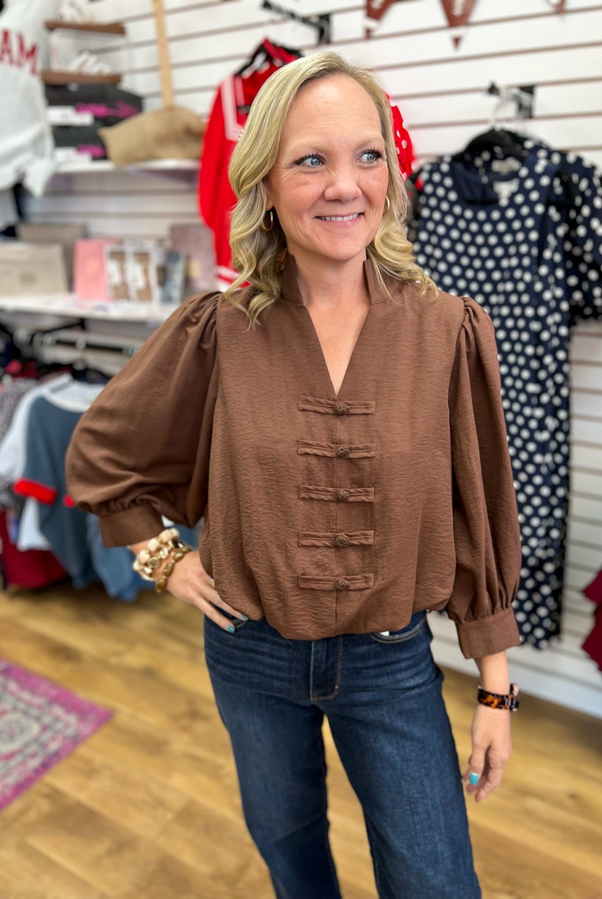 Brown v-neck puff sleeve top with frog closures and bubble hem on model