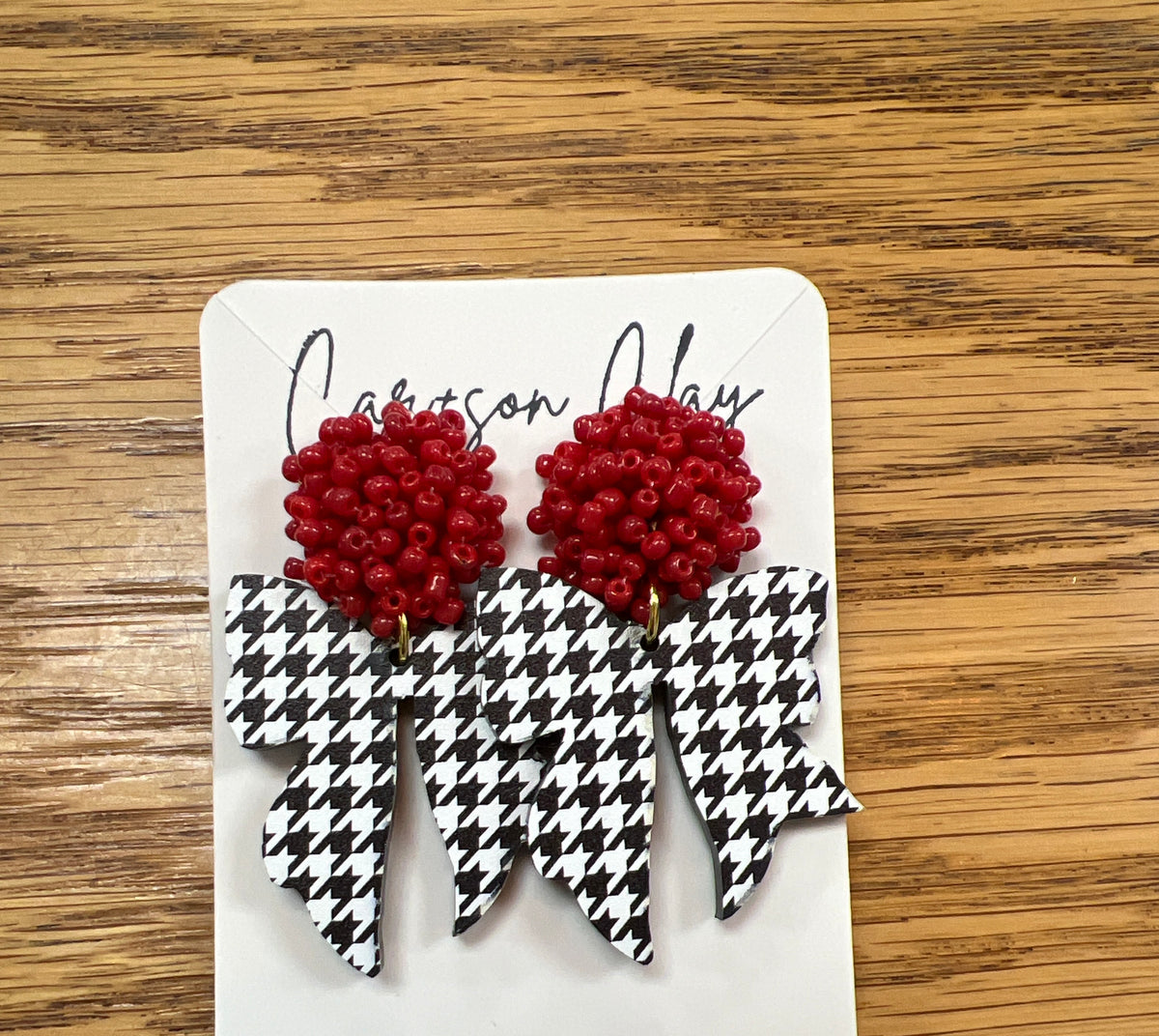 Red seed bead and black white houndstooth bow dangle earrings on display card