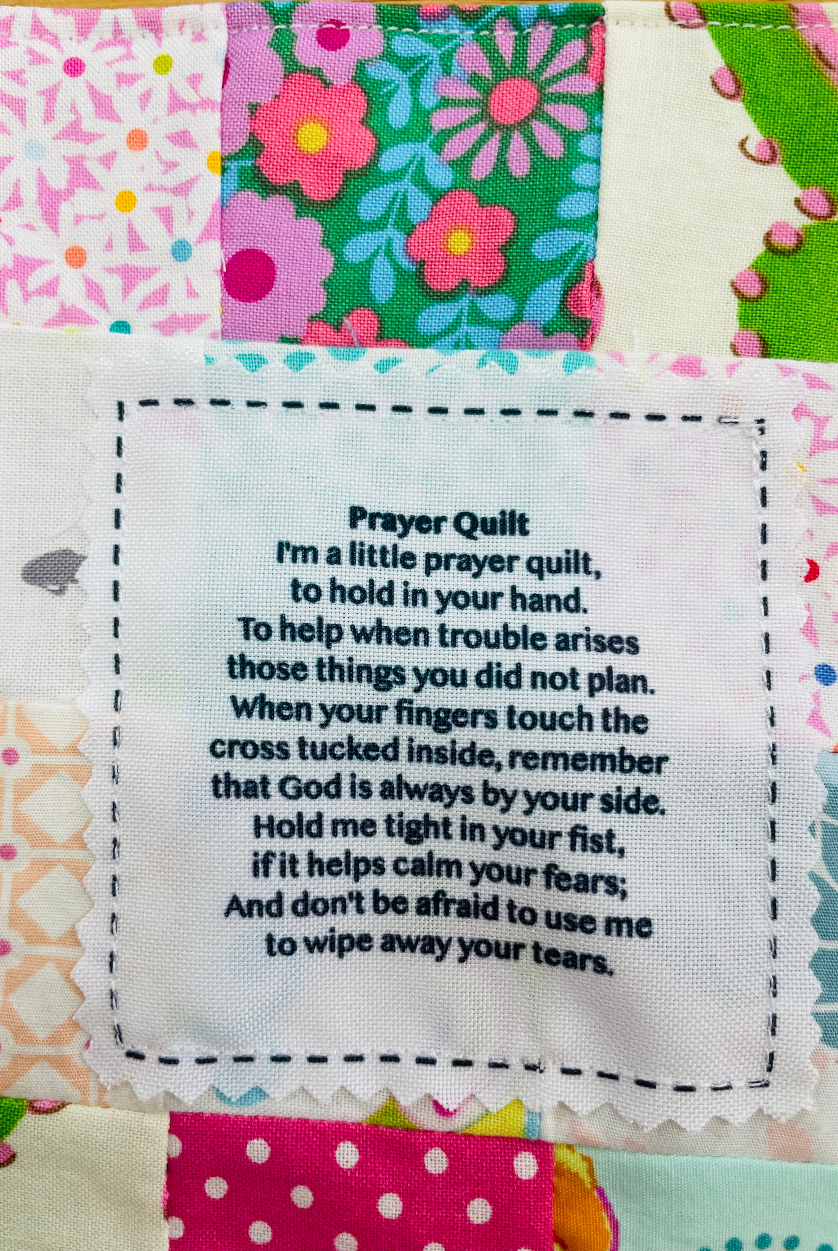 Colorful patchwork prayer quilt with white fabric label printed with poem text