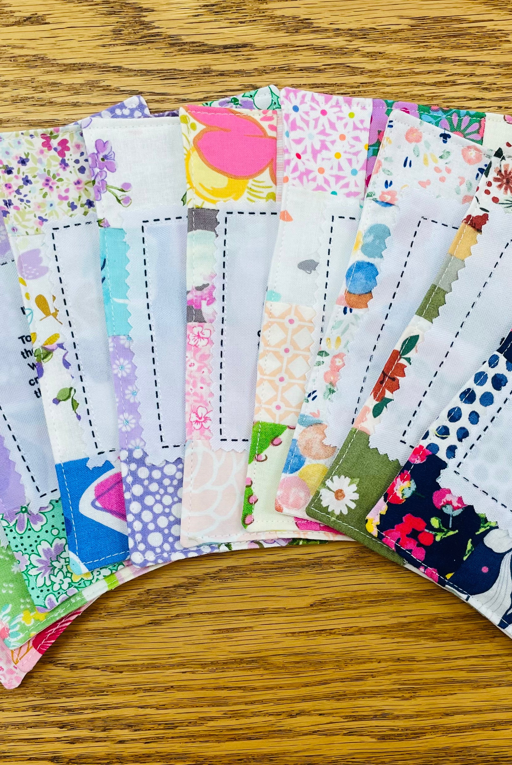 Handmade fabric prayer quilts in colorful floral patterns, fanned out on wood surface