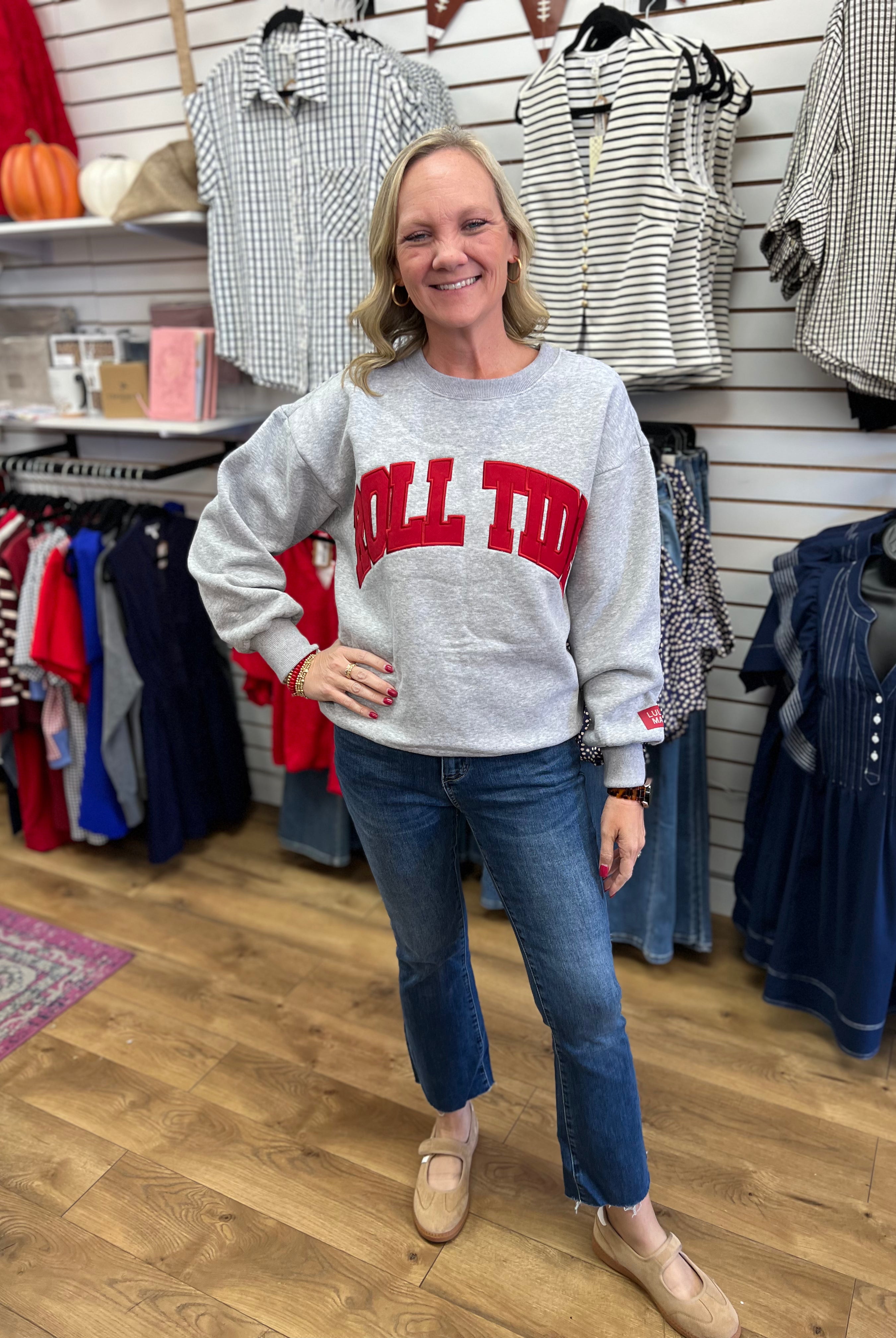 Grey crewneck sweatshirt with red Roll Tide lettering, worn with blue jeans