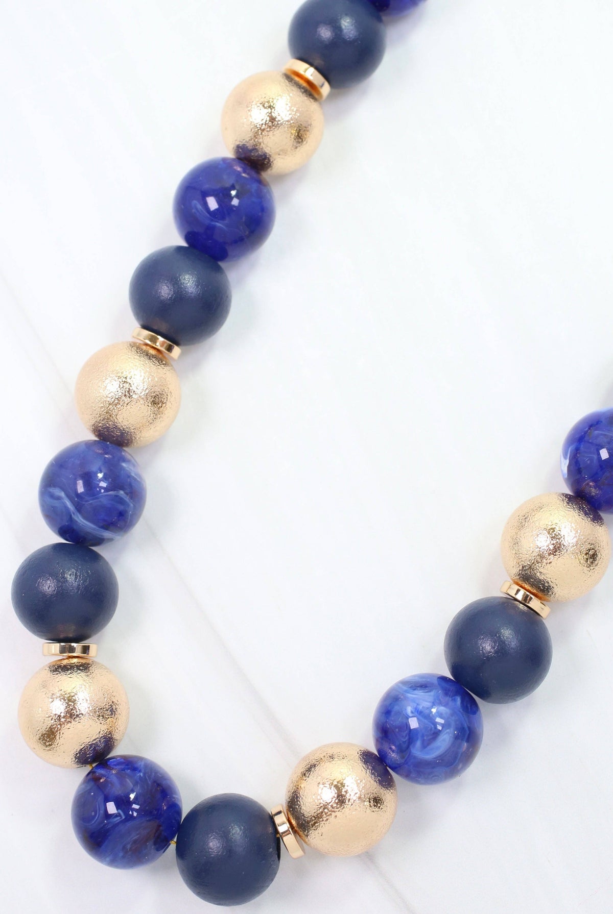 Navy and gold beaded ball necklace with matte, glossy, and textured round beads