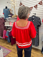 Red short sleeve top with white contrast stripe trim at neckline and hem