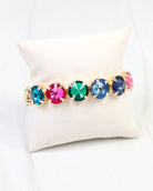 Multicolor rhinestone stretch bracelet with gold settings on a cream jewelry pillow