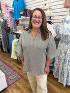 Black and white gingham v-neck top with 3/4 sleeves and button cuffs on model