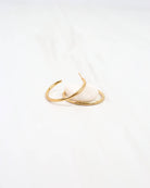 Caroline Hill Mayor thin gold hoop earrings displayed on a small white stone