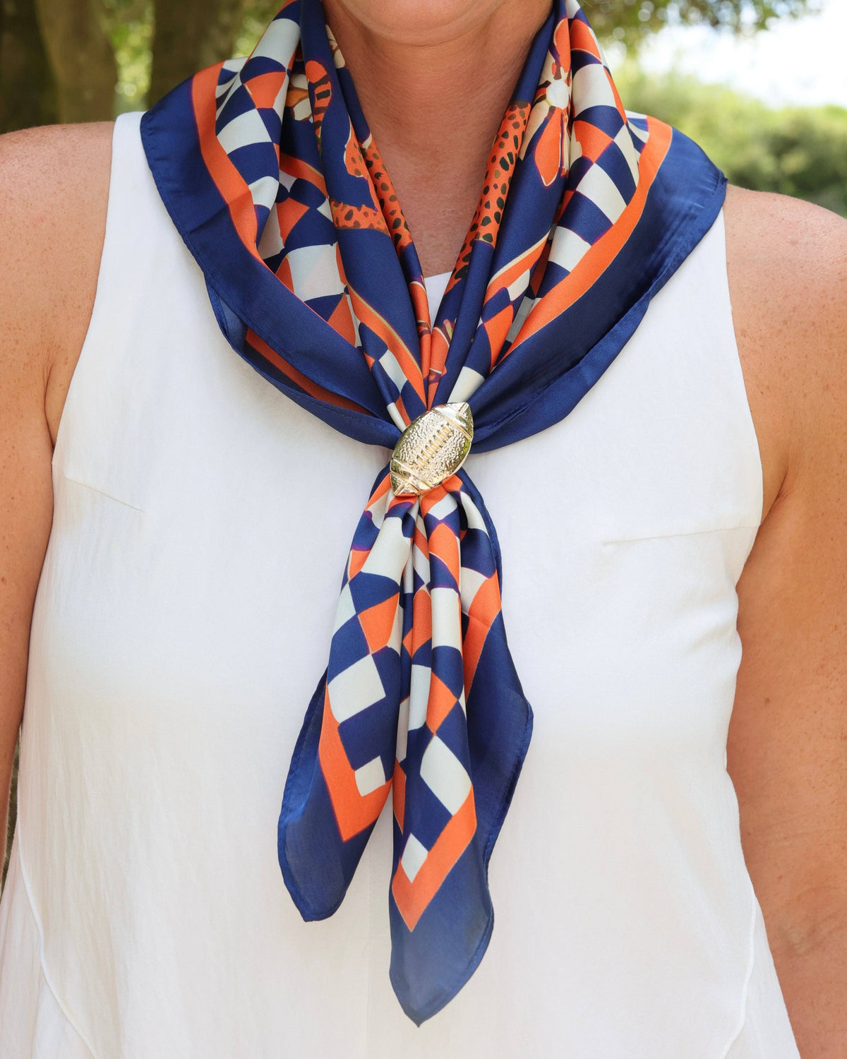 Navy and orange geometric silk scarf secured with gold football ring closure