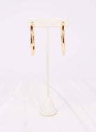 Caroline Hill Arden gold satin hoop earrings displayed on white jewelry stand