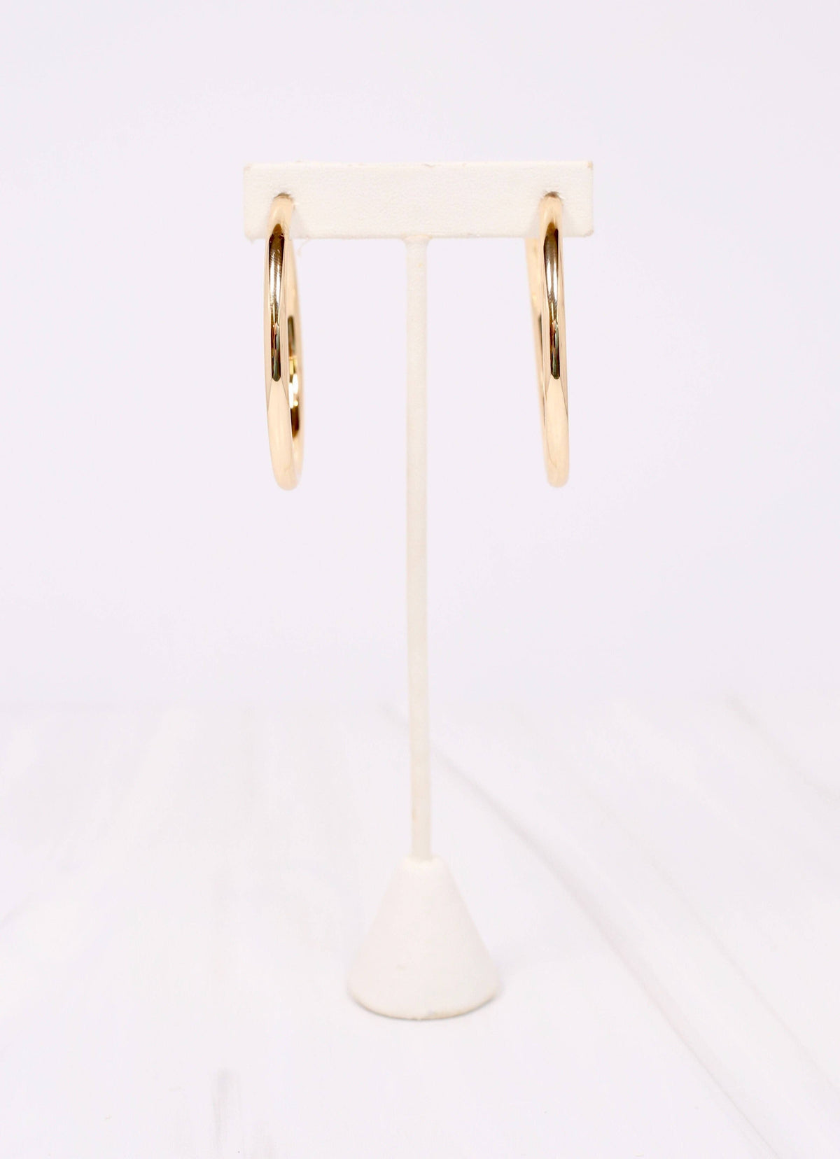 Caroline Hill Arden gold satin hoop earrings displayed on white jewelry stand