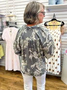Grey floral print Umgee top with 3/4 puff sleeves, back view, white pants