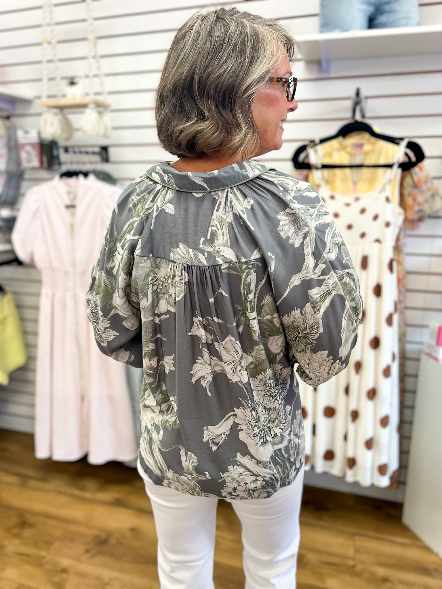 Grey floral print Umgee top with 3/4 puff sleeves, back view, white pants