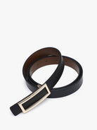 Reversible black and brown leather belt with gold rectangular frame buckle coiled flat