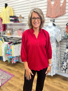 Wine red v-neck blouse with 3/4 balloon sleeves and scalloped hem on woman