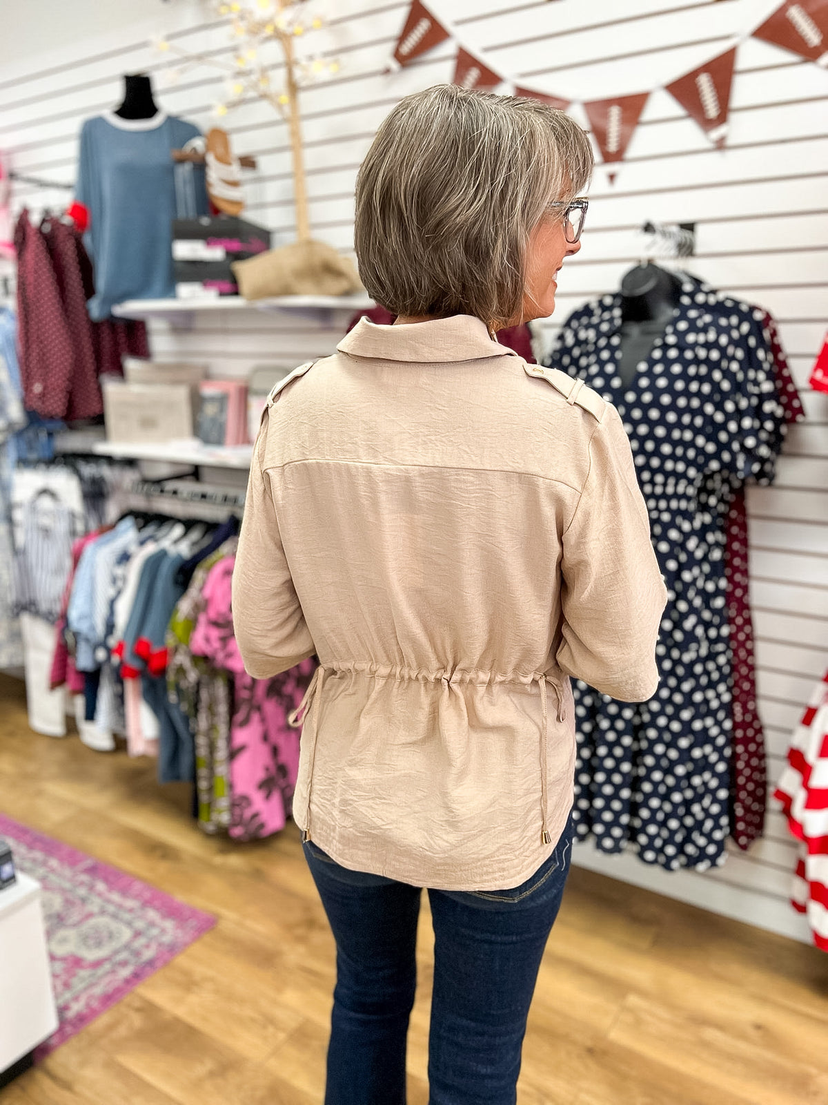 Light taupe utility jacket with drawstring waist and shoulder tabs, back view