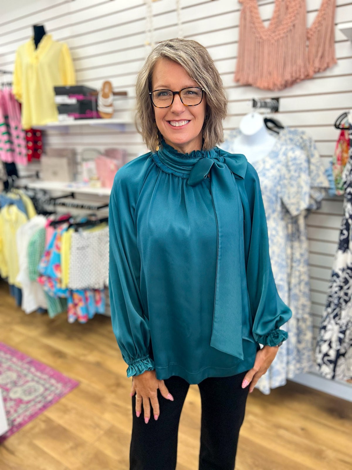 Teal green satin tie-neck blouse with balloon sleeves and ruffle cuffs on woman