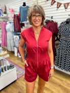 Garnet red zip-front cap sleeve romper with smocked waist on model