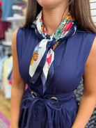 Navy sleeveless V-neck dress with tie belt and floral scarf accessory