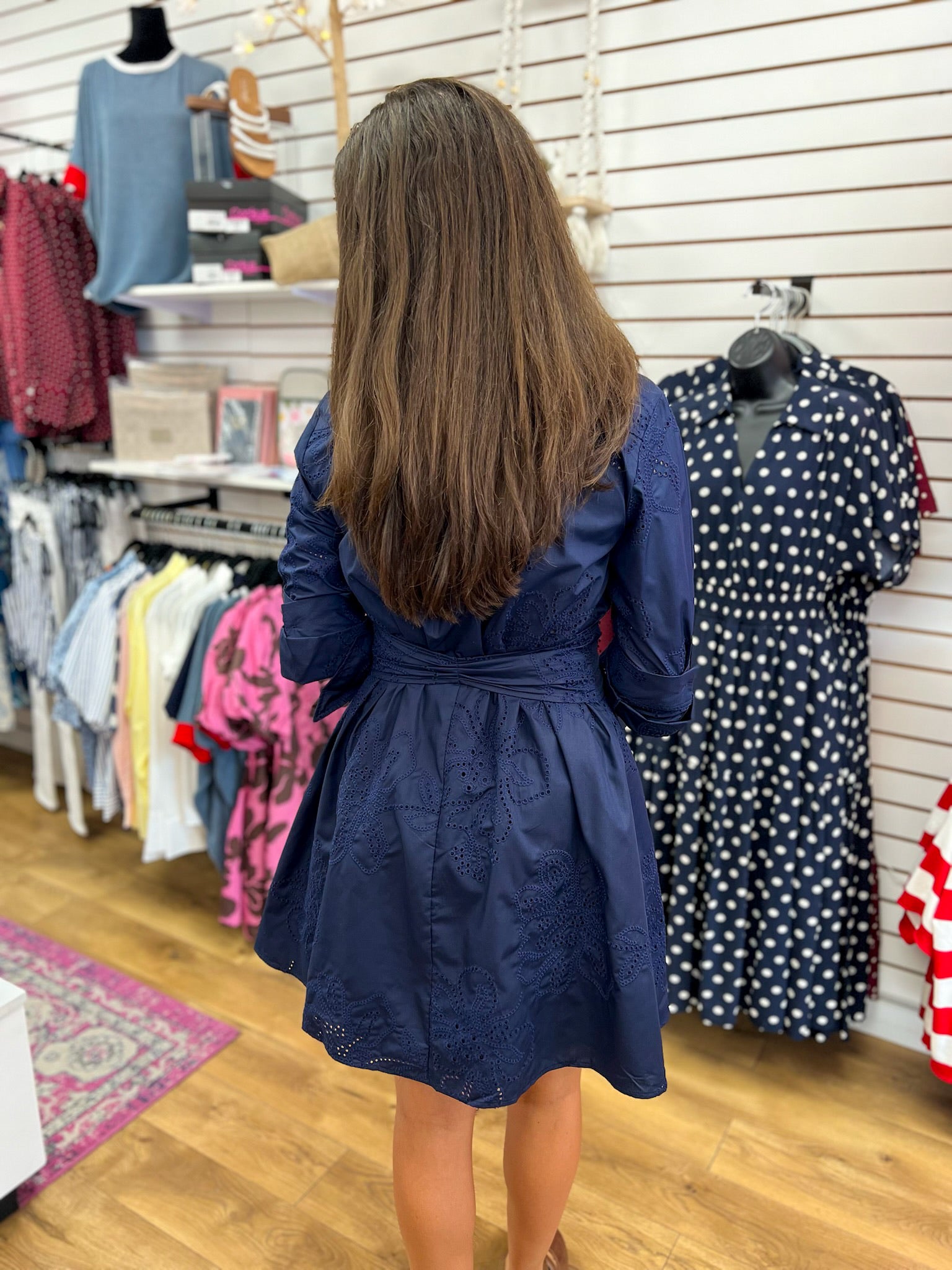 Navy blue eyelet floral pattern fit-and-flare dress with belted waist, back view