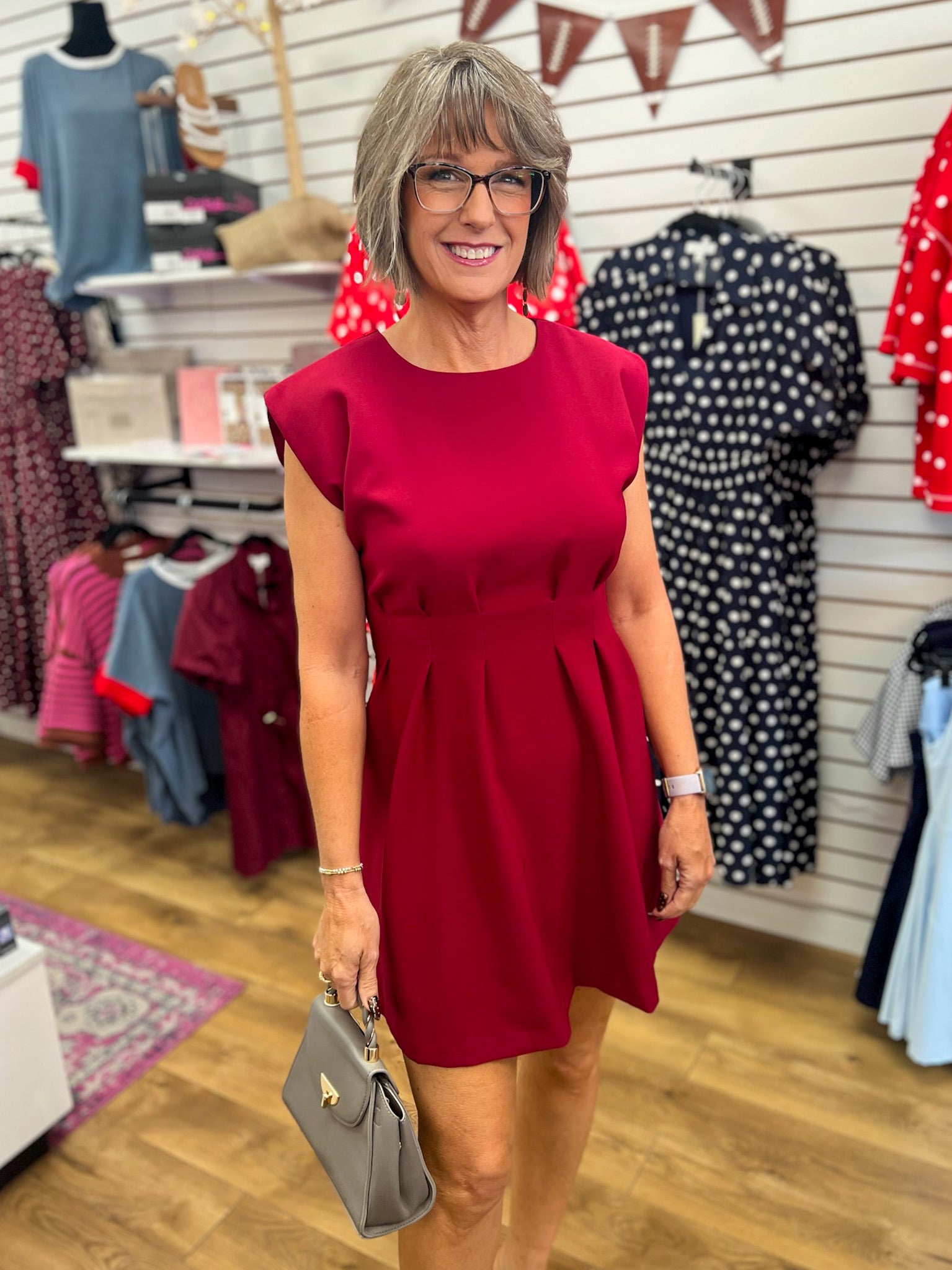 Burgundy sleeveless A-line dress with pleated waist and structured shoulders