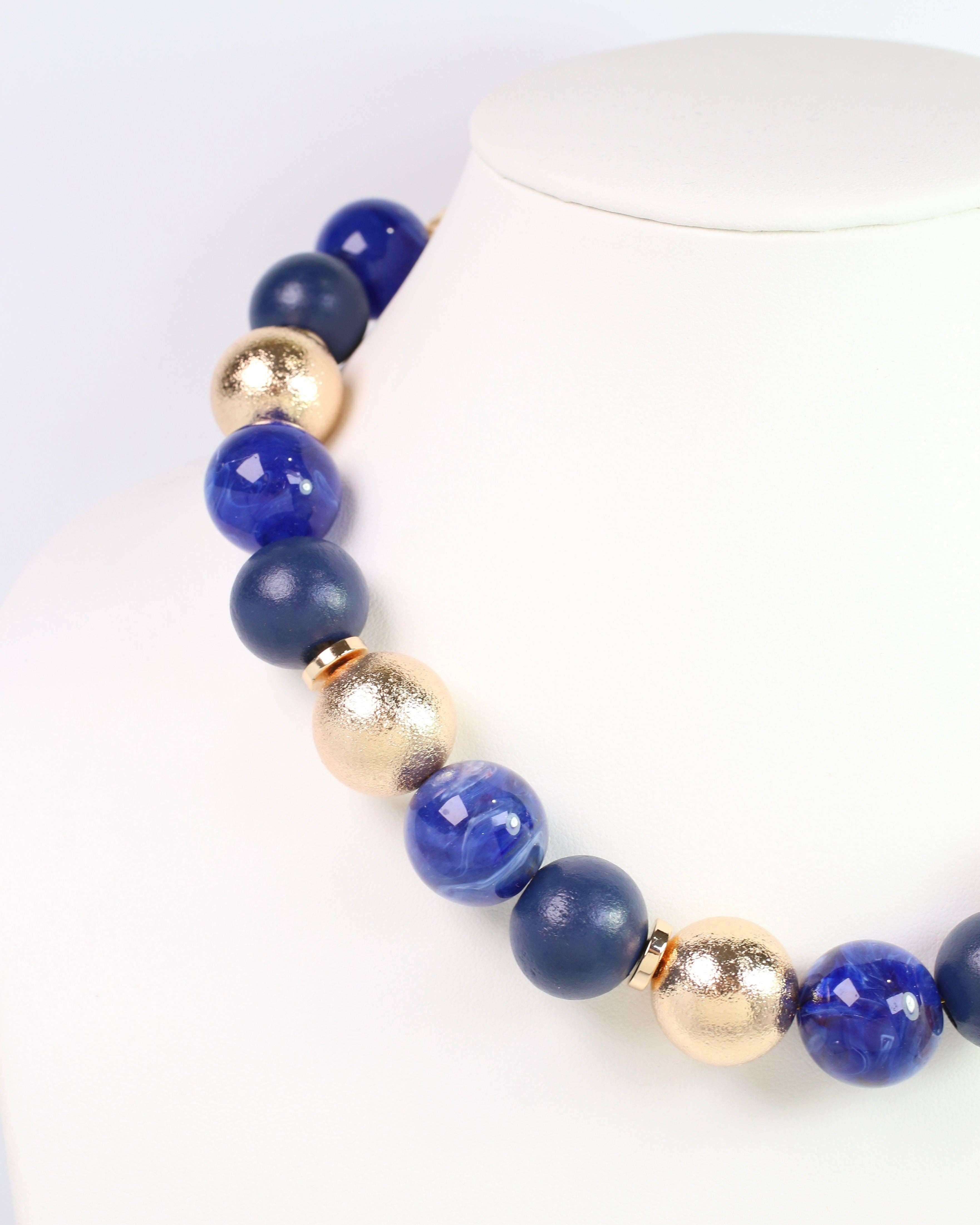Caroline Hill Elaine navy blue and gold beaded ball statement necklace on display