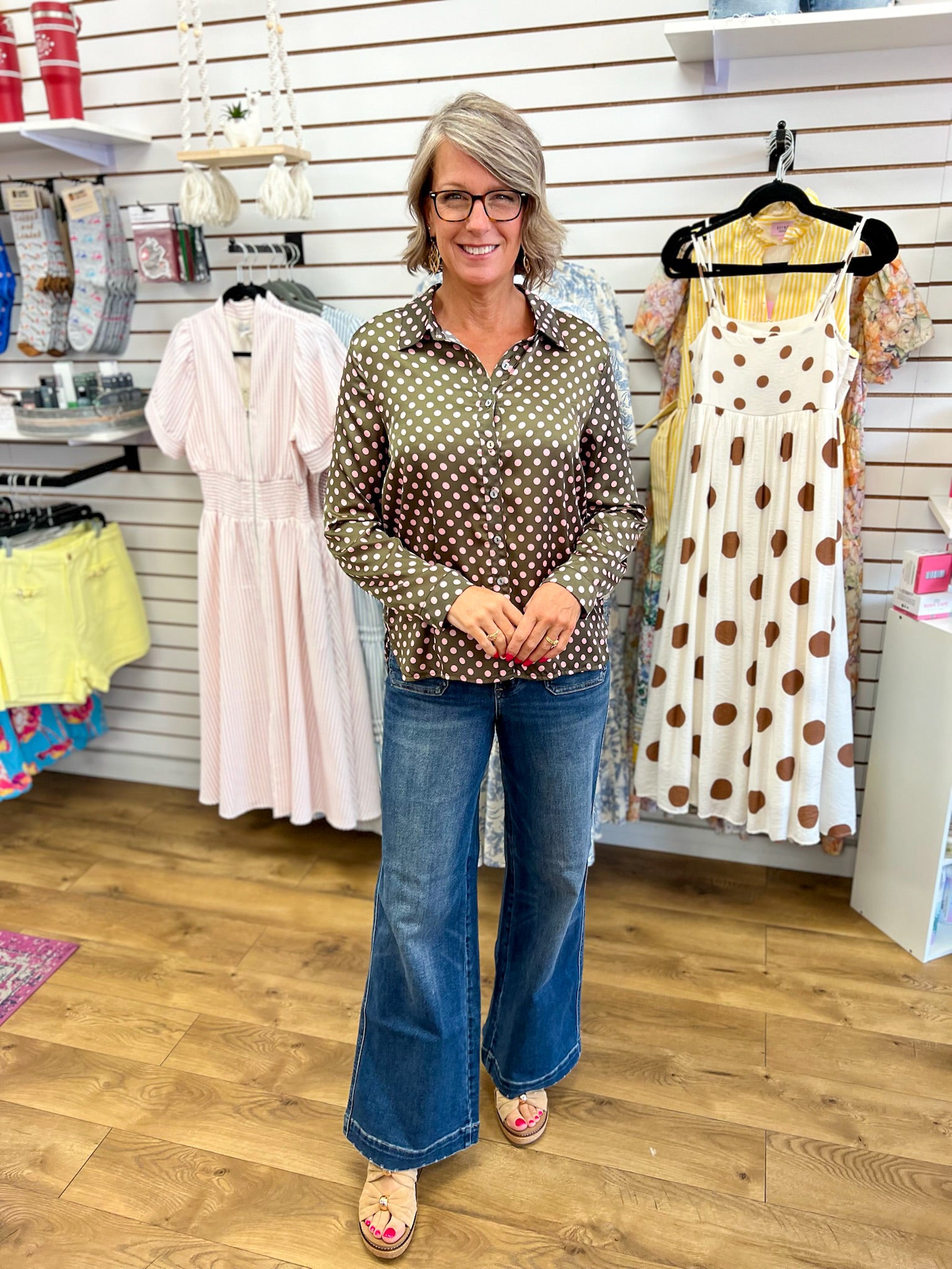 Olive satin long sleeve button-up shirt with pink polka dots, worn with wide-leg jeans
