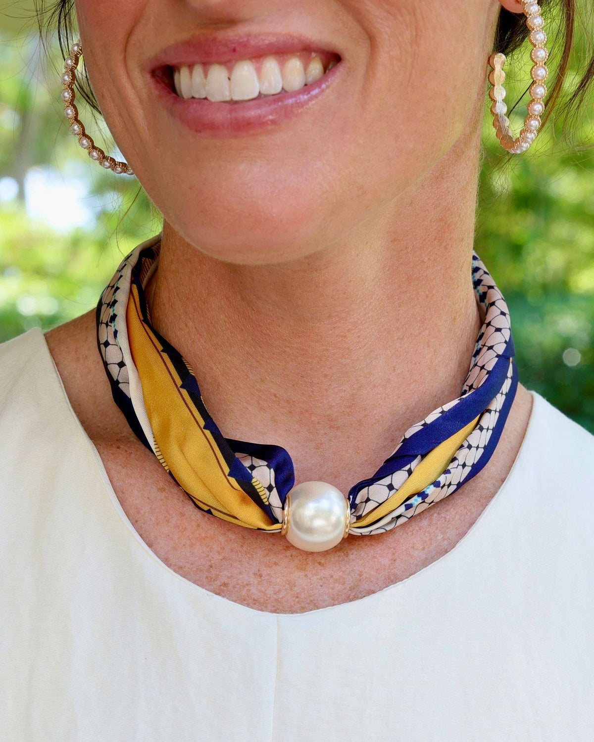 Navy yellow patterned silk scarf twisted into necklace secured with large pearl magnetic clasp