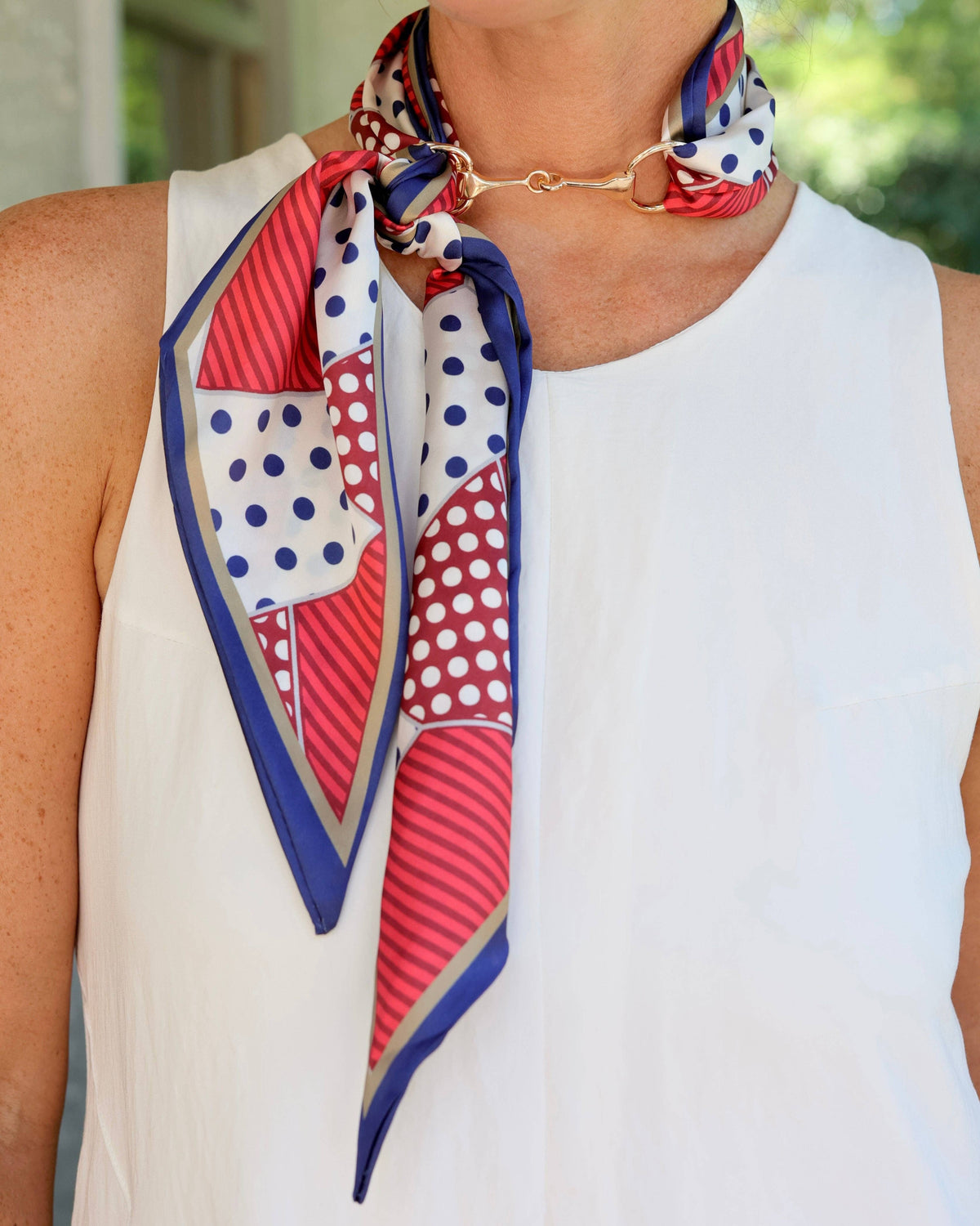 Navy red polka dot stripe silk scarf tied with gold horsebit buckle necklace