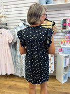 Black polka dot mini dress with ruffle sleeves, mock neck, and gathered back