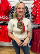 Ecru puff sleeve knit top styled with detachable leopard print red trim scarf