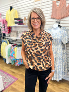 Brown leopard print sleeveless mock neck top with metallic threads on smiling woman