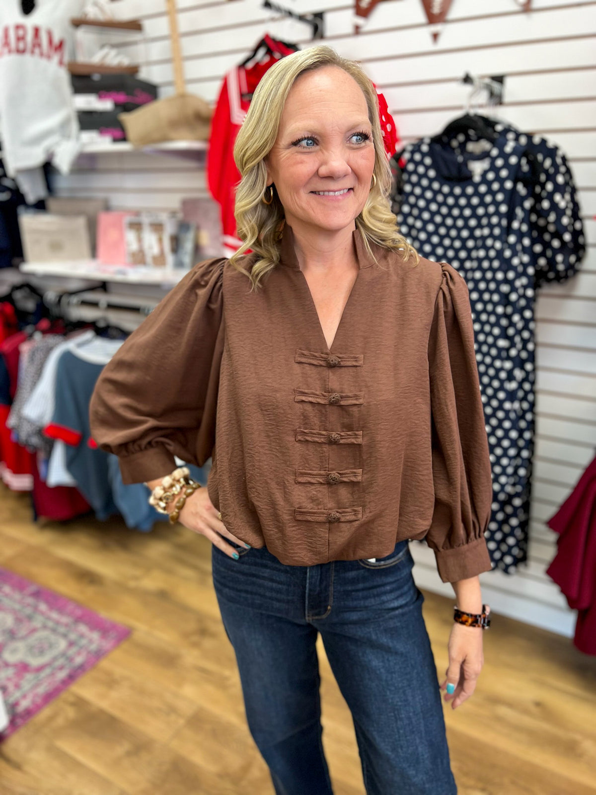 Brown v-neck puff sleeve top with frog closures and bubble hem on model