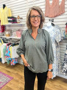 Olive grey V-neck blouse with 3/4 balloon sleeves and contrast stitching on model