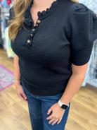 Black short sleeve knit sweater with ruffle neckline and gold front buttons