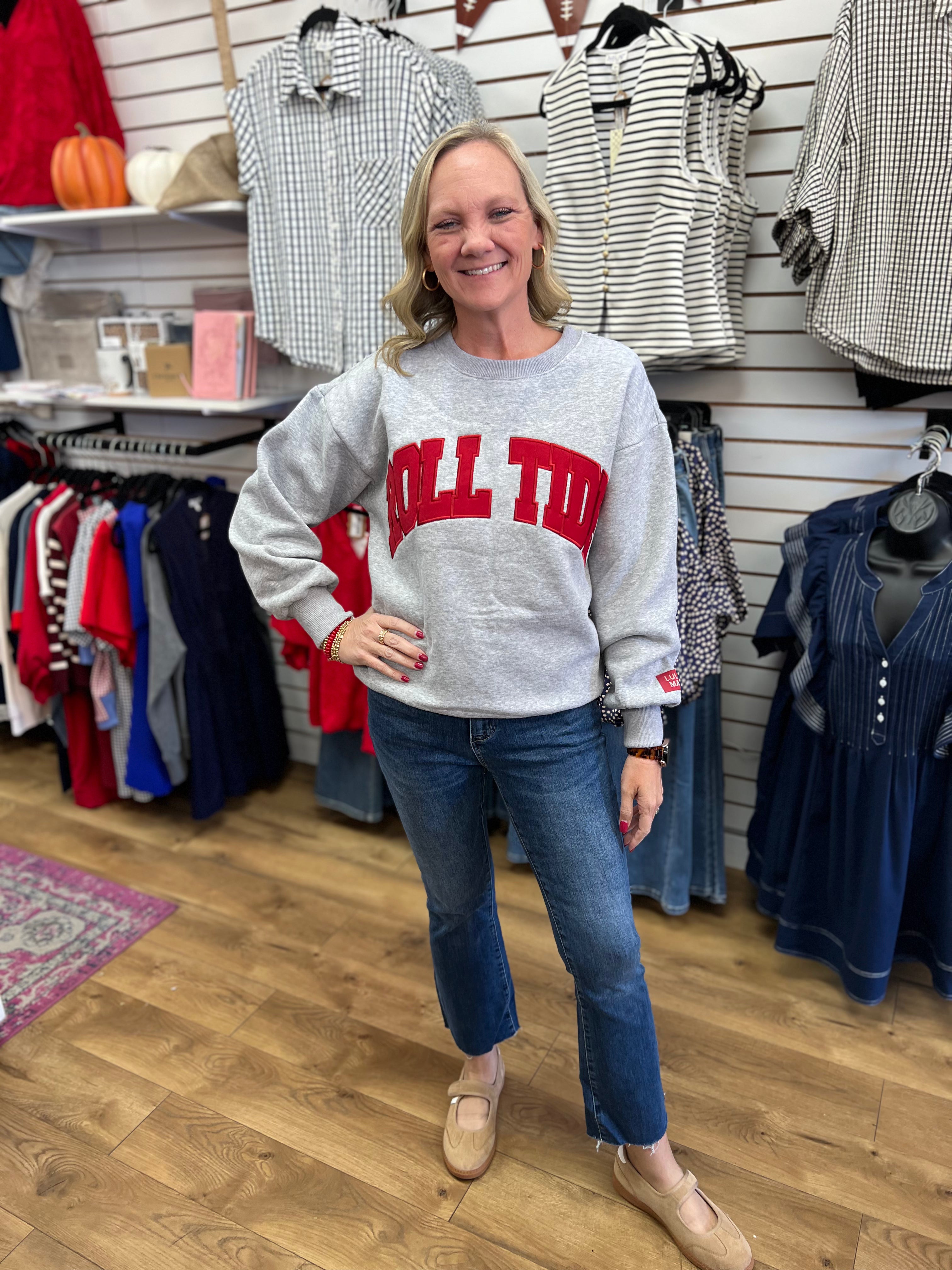 Grey crewneck sweatshirt with red Roll Tide lettering, worn with blue jeans