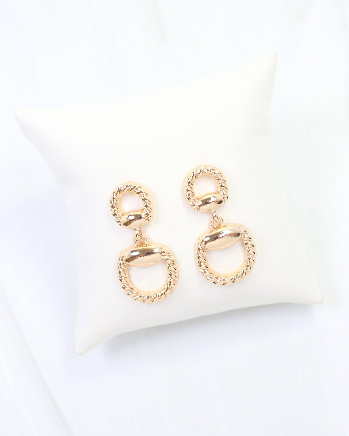Gold braided horsebit drop earrings with twisted rope detail on ivory display pillow