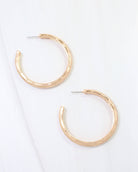 Pair of large gold hammered hoop earrings with worn patina and post backs