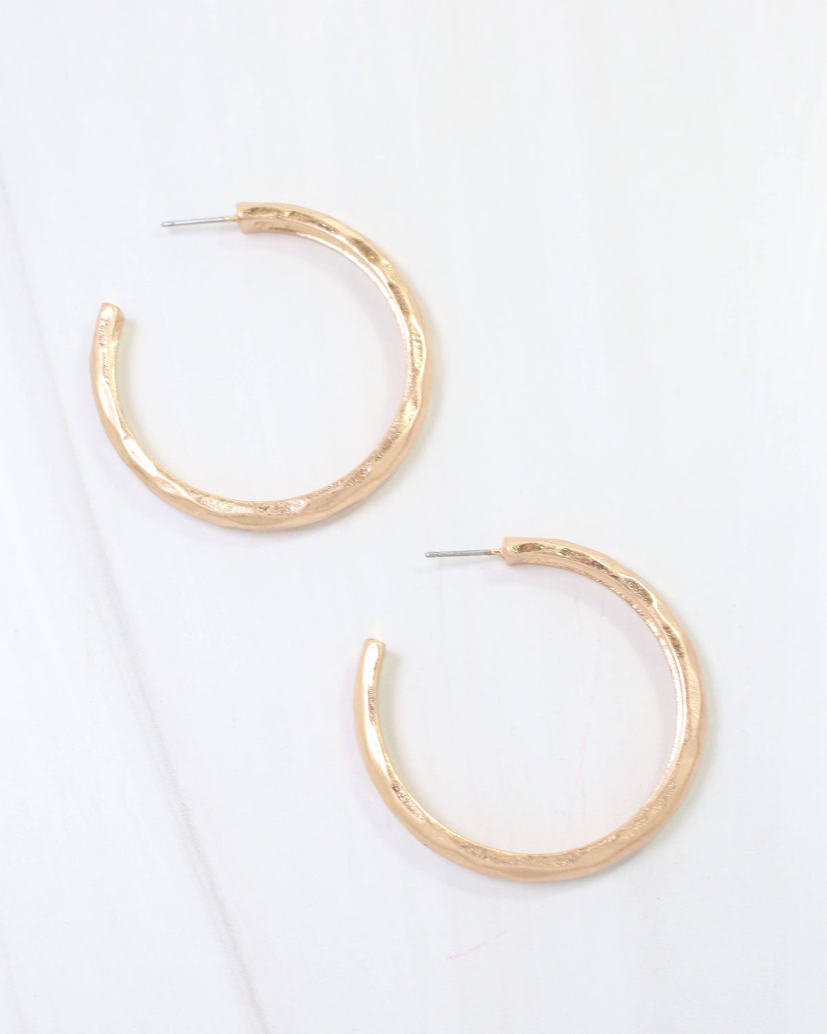 Pair of large gold hammered hoop earrings with worn patina and post backs
