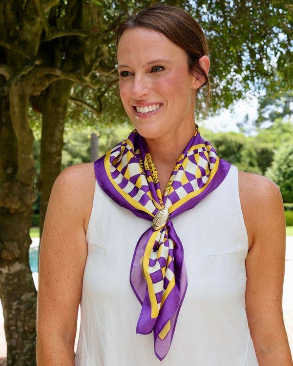 Purple and gold checkered silk scarf with decorative clasp worn around neck