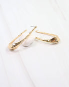 Caroline Hill Fairfield gold hammered hoop earrings with elongated oval shape on marble surface