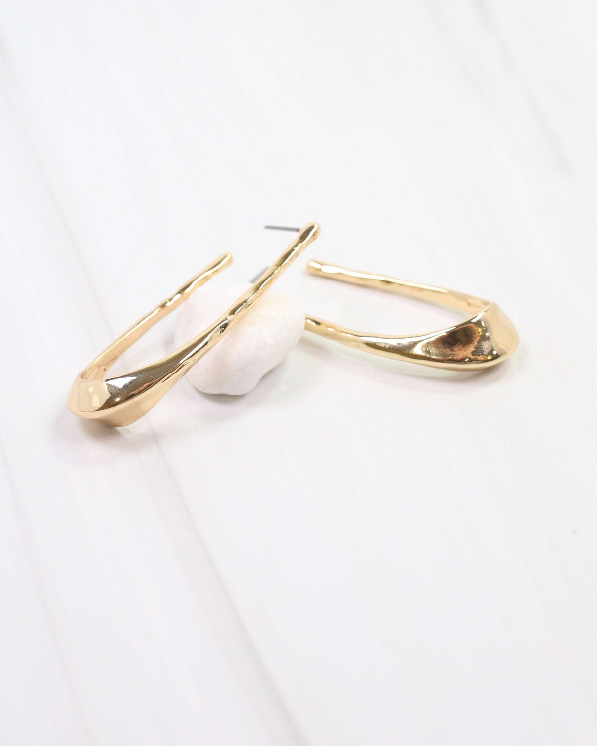 Caroline Hill Fairfield gold hammered hoop earrings with elongated oval shape on marble surface