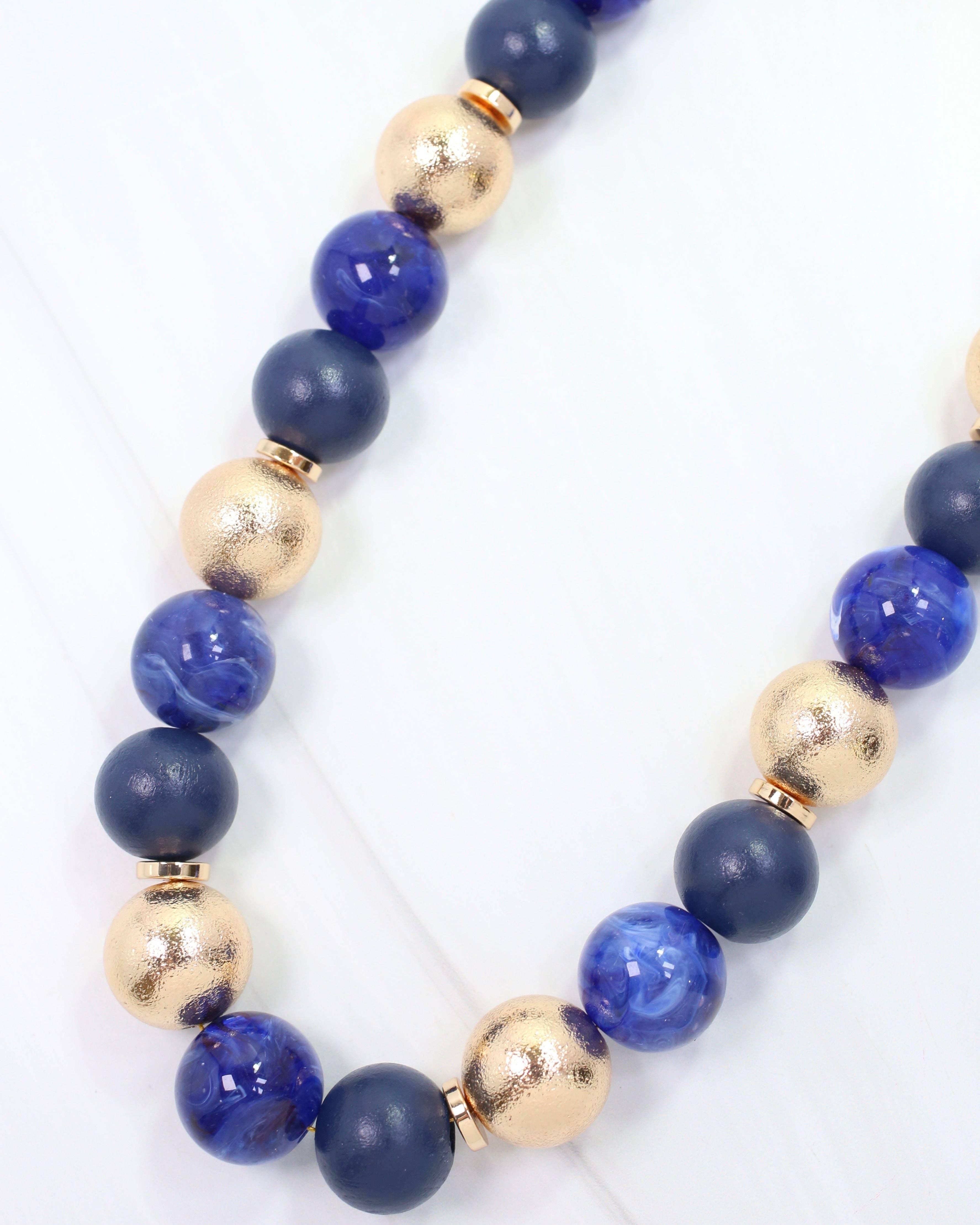 Navy and gold beaded ball necklace with matte, glossy, and textured round beads