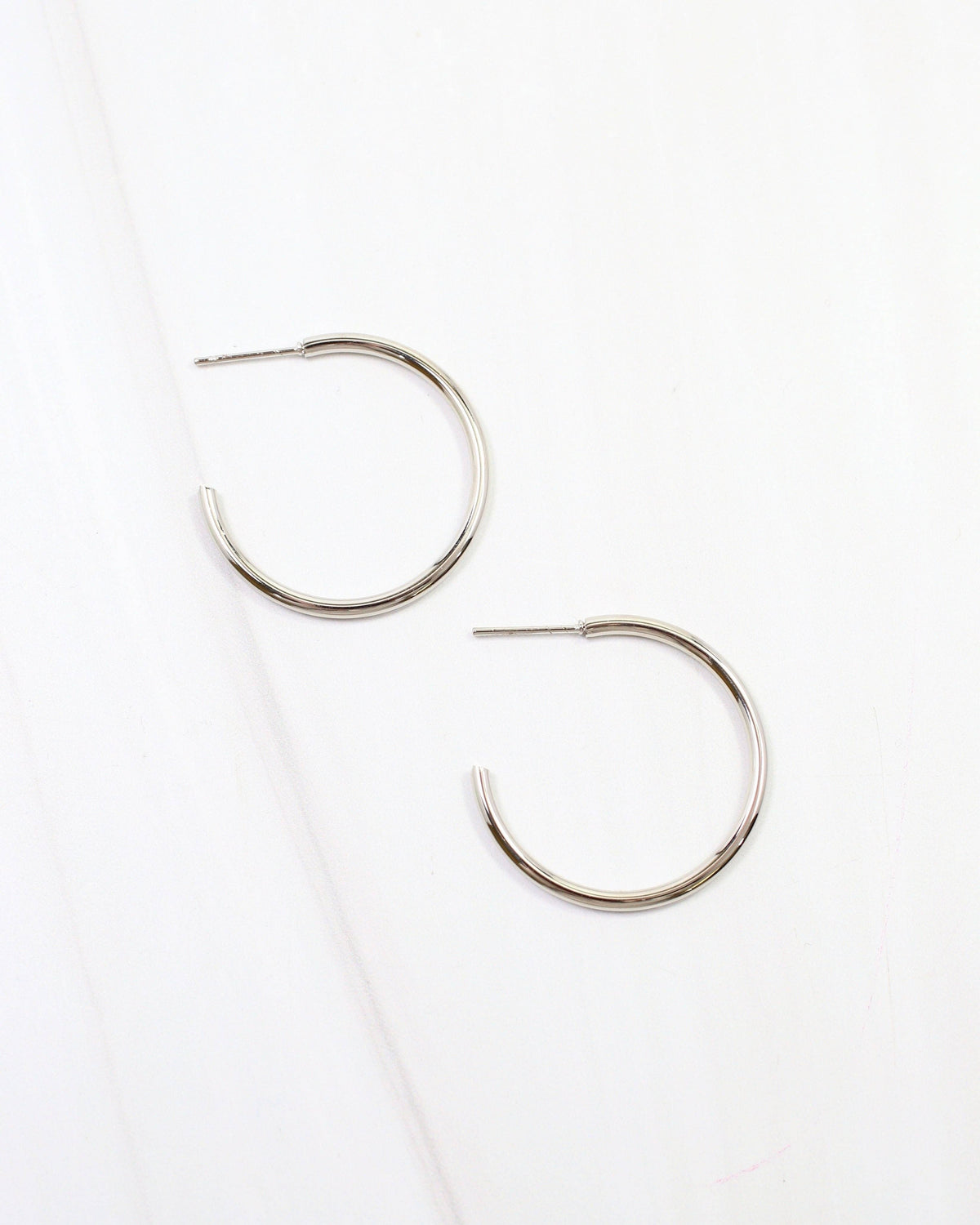 Caroline Hill Mayor thin silver hoop earrings with post backs on white marble