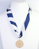 Navy and white striped skinny scarf with gold medallion pendant on mannequin