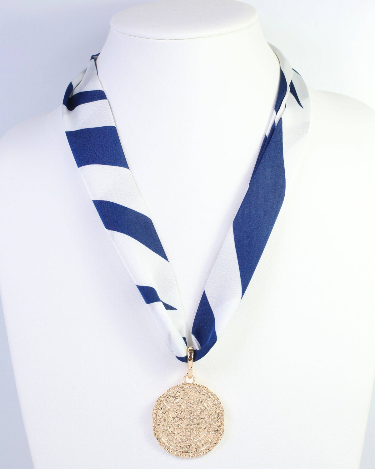 Navy and white striped skinny scarf with gold medallion pendant on mannequin
