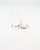 Caroline Hill Mayor thin silver hoop earrings displayed on white surface with stone prop